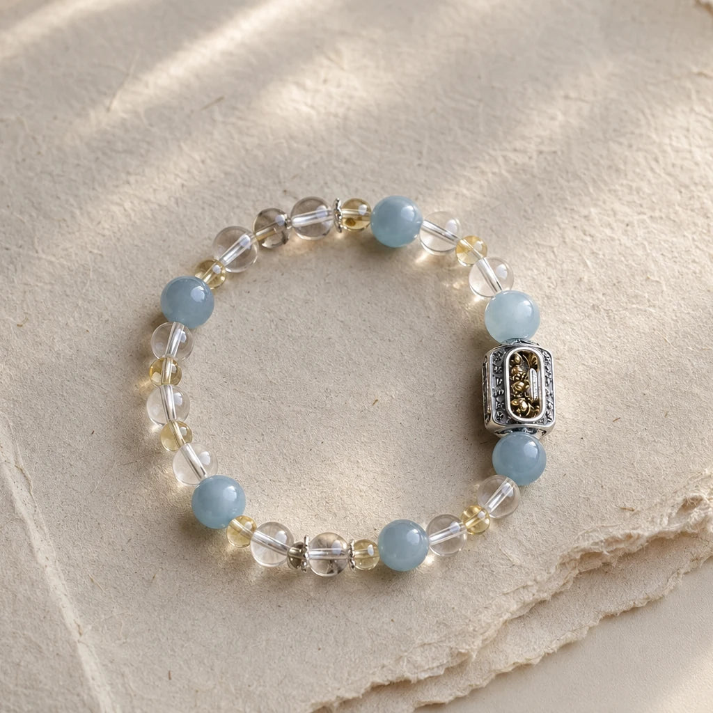 Still Ground Plan B bracelet with pale blue, clear, smoky-clear, and soft yellow beads on handmade paper